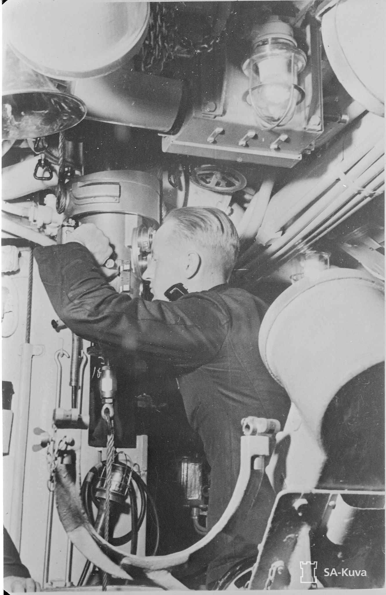 Equipment needed in command, navigation and control is located in the control room of the submarine. Captain lieutenant Pentti Airaksinen, commanding officer of Vesikko, is at the periscope in summer 1942. Photo: Military Museum. 
